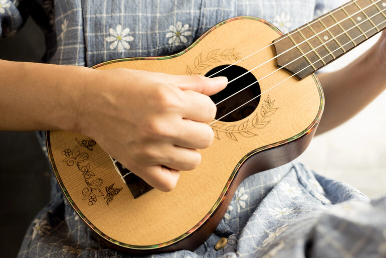 Young woman playing on ukulele