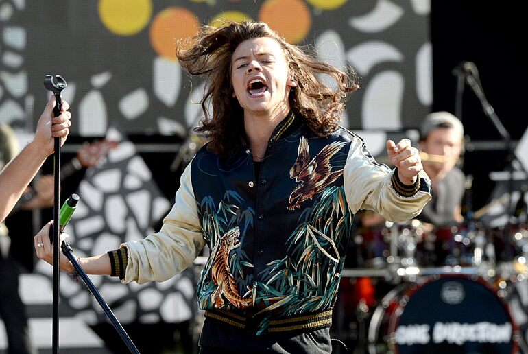A performer with Harry Styles passionately singing on stage