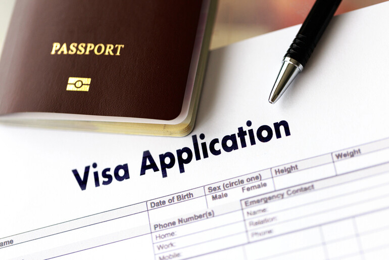Visa application form with passport and pen representing investment-based residency opportunities.